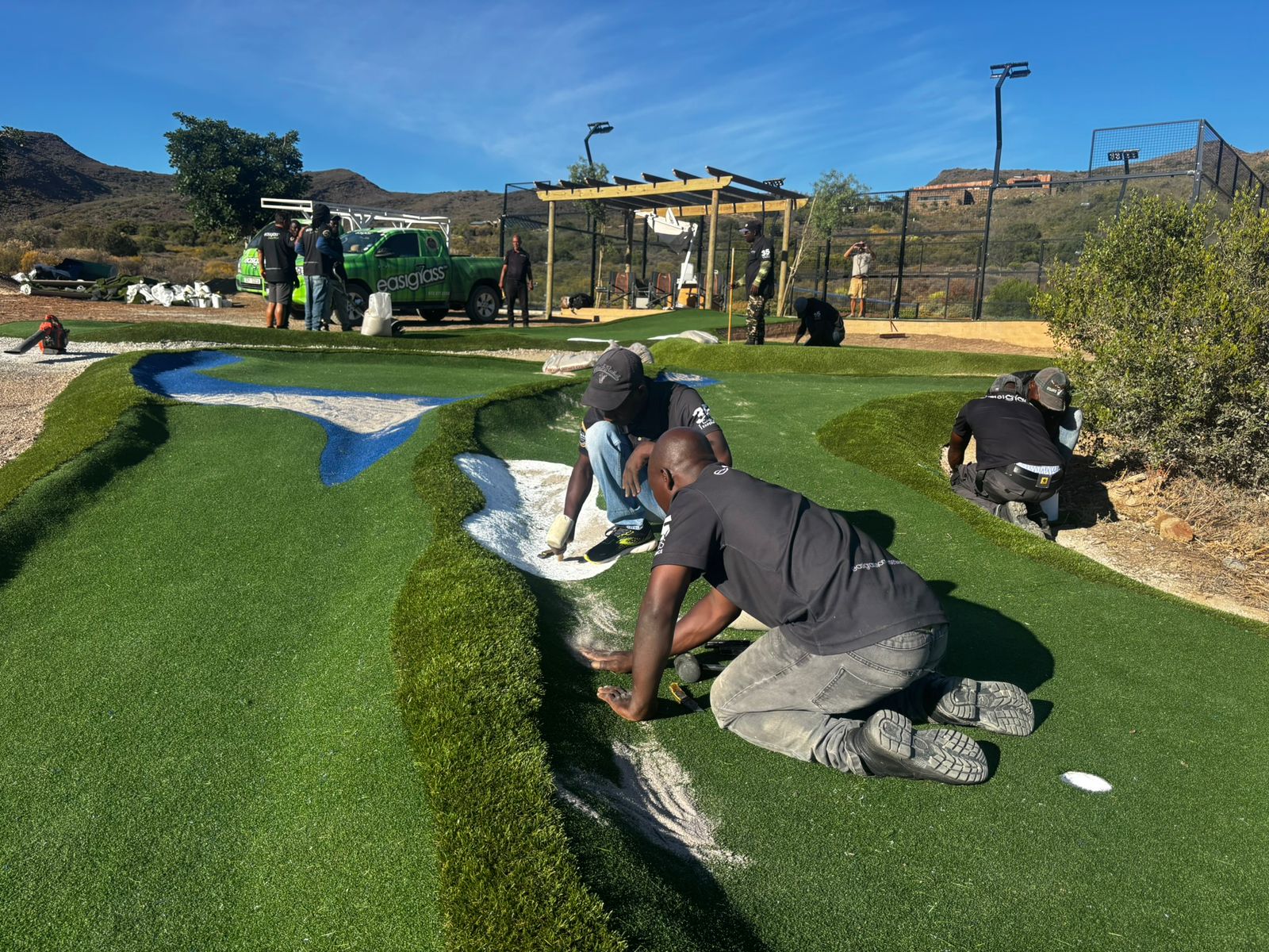 The Kimko and Easigrass team hand-finishing an artificial grass putting green on site
